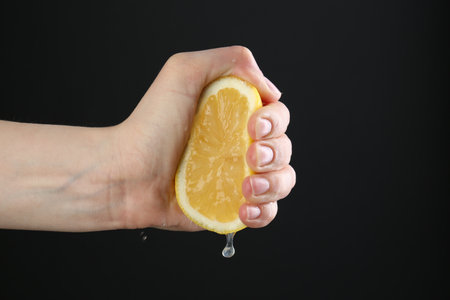 Woman squeezing lemon on black background, closeupの写真素材