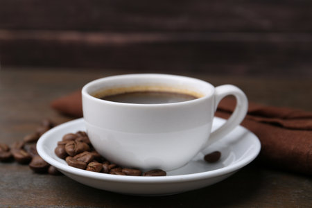 Aromatic coffee in cup, beans and saucer on wooden table, closeupの写真素材