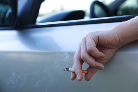 Man smoking while driving in car, focus on cigarette. Space for textの写真素材