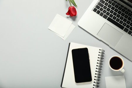 Flat lay composition with stationery, phone, coffee and flower on light grey background. Space for...