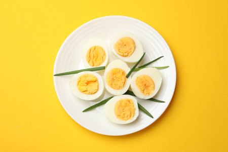 Boiled eggs and green onions on yellow background, top viewの写真素材