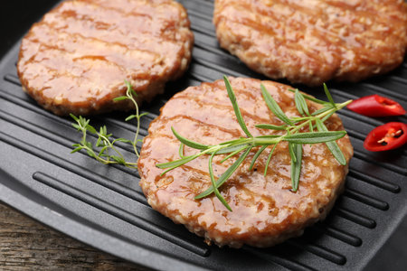 Delicious hamburger patties and spices in frying pan on table, closeupの写真素材