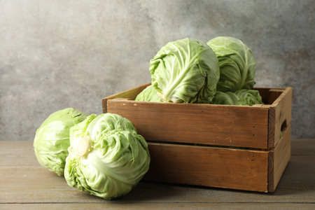 Fresh whole cabbages and crate on wooden tableの写真素材