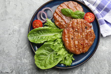 Delicious hamburger patties, tomato, lettuce and spices on grey table, top viewの写真素材