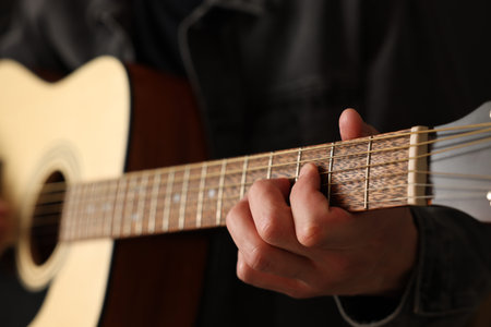 Man playing guitar on black background, closeup