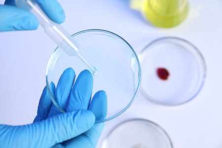 Scientist with Petri dishes and pipette on white background, closeup