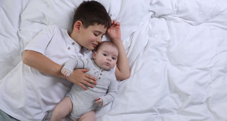 Cute little brothers on bed, top view. Space for text