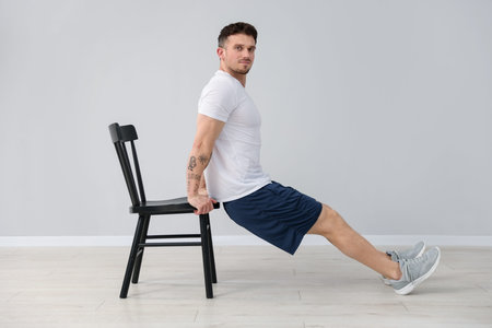 Handsome man exercising with chair at home