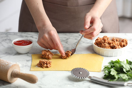 Woman making ravioli bolognese at white marble table, closeupの写真素材