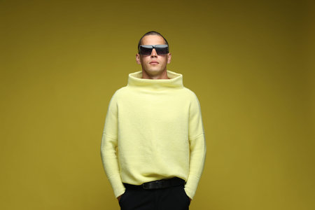 Fashionable portrait of handsome man in stylish outfit on olive background
