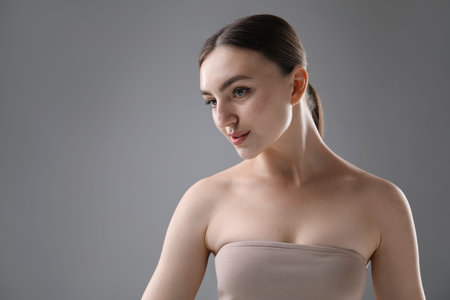 Portrait of beautiful woman on grey background. Space for text