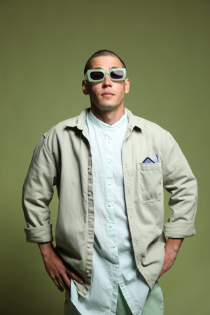 Fashionable portrait of handsome man in stylish outfit on green background