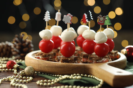 Tasty canapes and Christmas decor on wooden table against background with blurred lights, closeup. Bokeh effectの写真素材