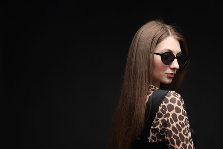 Fashionable portrait of beautiful woman in stylish outfit on black background. Space for textの写真素材