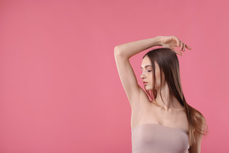Young woman showing smooth skin after epilation on pink background, space for textの写真素材
