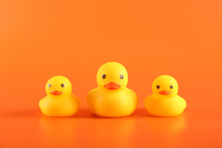 Three cute rubber ducks on orange backgroundの写真素材