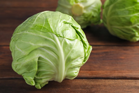Fresh whole cabbages on wooden table, closeup. Space for textの写真素材