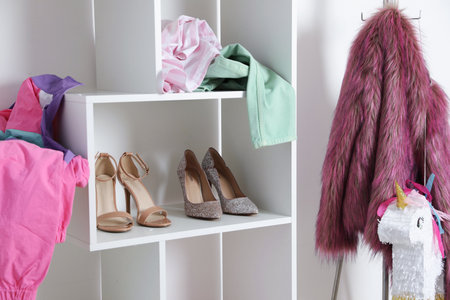 Shelving unit with different footwear and clothes indoors. Shoe storageの写真素材