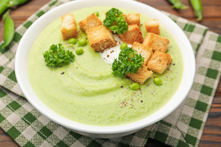 Tasty pea cream soup with croutons and broccoli served on wooden table, closeupの写真素材