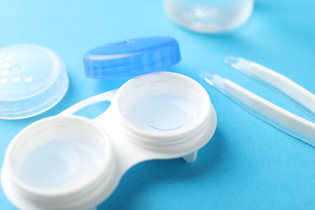 Contact lenses in case and tweezers on light blue background, closeupの写真素材
