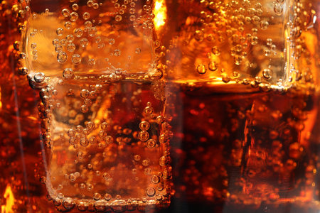 Refreshing cola with ice cubes as background, macro viewの写真素材