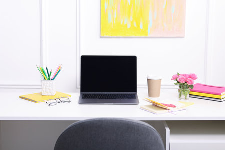 Workplace with laptop and beautiful flowers in officeの写真素材