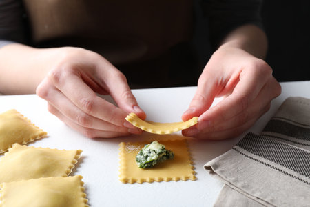 Woman making ravioli with cheese and spinach at white table, closeupの写真素材
