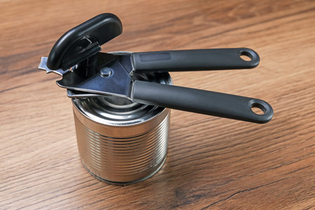 Can opener and tin on wooden table, closeupの写真素材