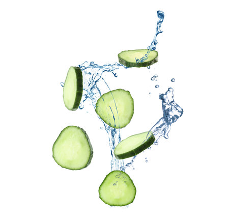 Cucumber slices and splashing water in air on white backgroundの写真素材