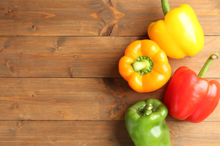 Ripe colorful bell peppers on wooden table, flat lay. Space for textの写真素材
