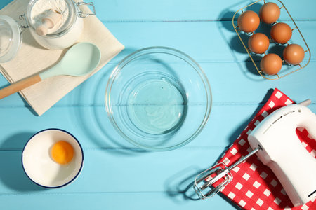 Making whipped cream. Bowl, hand mixer and ingredients on light blue wooden table, flat layの写真素材
