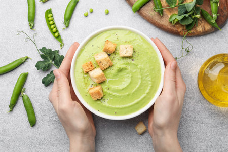 Woman having tasty pea cream soup with croutons at grey table, top viewの写真素材