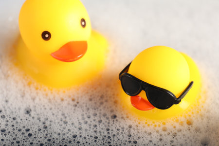 Cute rubber ducks floating in water with foam, closeupの写真素材