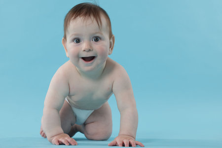 Cute little baby crawling on light blue background