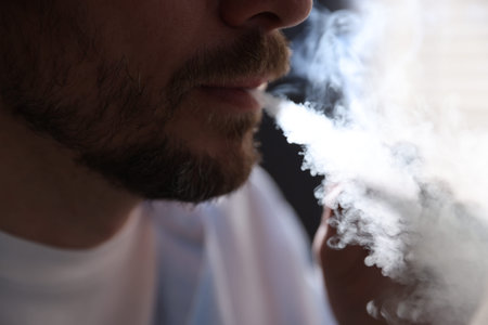 Man smoking cigarette on blurred background, closeup