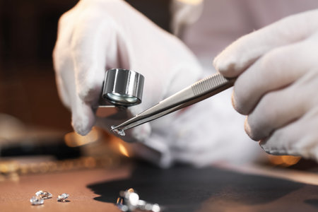 Appraiser with loupe evaluating gemstone at table indoors, closeupの写真素材