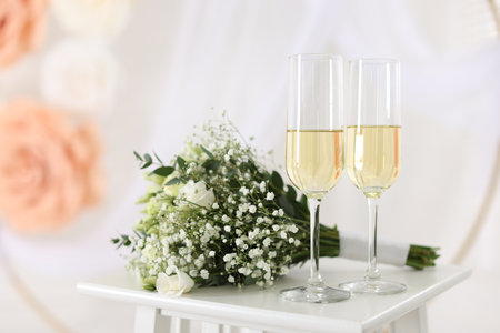 Glasses of champagne and wedding bouquet on table indoors, closeupの写真素材