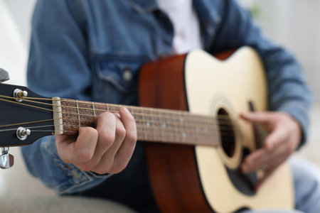 Man playing guitar on armchair indoors, closeupの写真素材