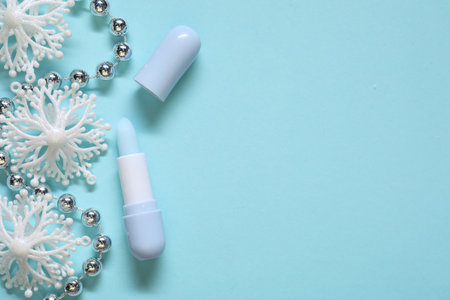 Moisturizing lip balm and Christmas decor on light blue background, flat lay. Space for textの写真素材