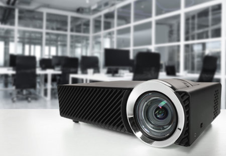 Modern video projector on white table in office