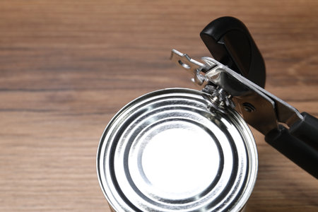 Can opener and tin on wooden table, closeup. Space for textの写真素材