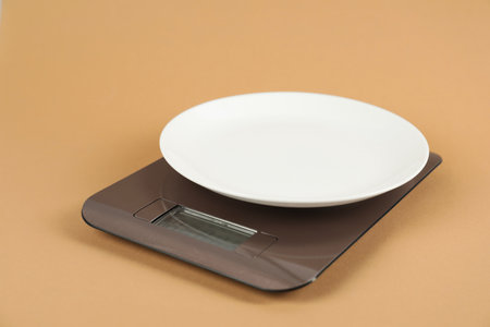 Electronic kitchen scale with empty plate on beige background, closeupの写真素材