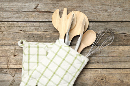 Different kitchen utensils in oven mitten on wooden table, top viewの写真素材