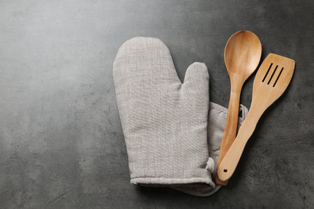 Spoon, spatula and oven mitten on grey table, flat lay. Space for textの写真素材