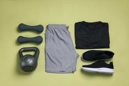 Sportswear, sneakers, dumbbells and kettlebell on pale olive background, flat layの写真素材