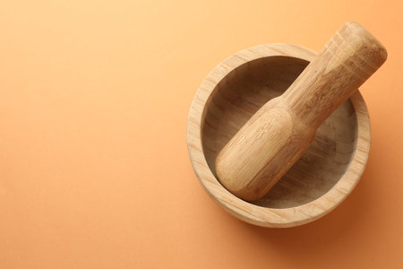 Wooden mortar and pestle on light brown background, top view. Space for textの写真素材