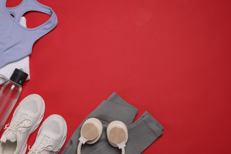 Sportswear, sneakers, towel, headphones and water bottle on red background, flat lay. Space for textの写真素材