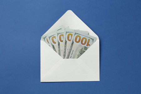 Money bonus. Envelope with dollar banknotes on blue background, top viewの写真素材