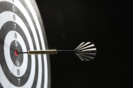 Targeting. Dart board with arrow on dark background, closeup