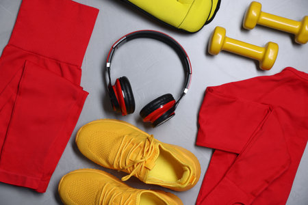 Sportswear, sneakers, ankle weights, dumbbells and headphones on gray textured background, flat layの写真素材